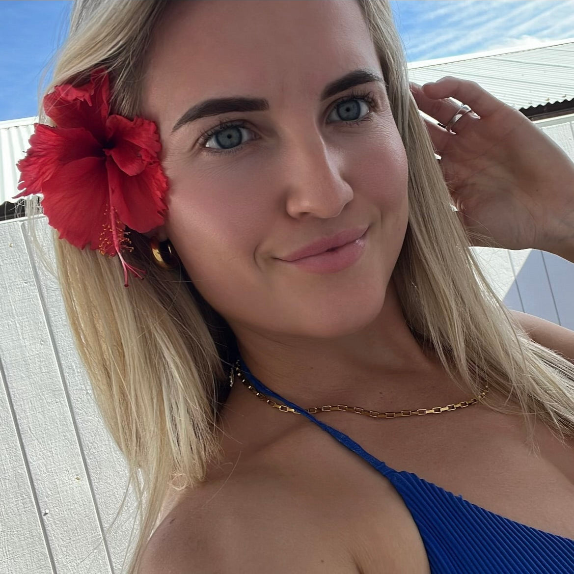 Woman with a red flower in her hair against a blue sky